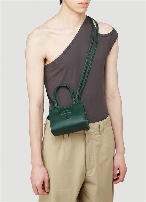 Green telfar bag - The iconic Unisex Shopping Bag is an Everyday bag for Everyone. Featuring a double strap (handles and cross-body straps), embossed logo, a main compartment with magnetic snap closure, internal laptop-sized compartment with zipper closure in back and additional internal pocket in front. Made from faux leather and twill